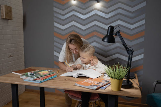 A mother assists her son with homework at a desk, fostering a learning environment.