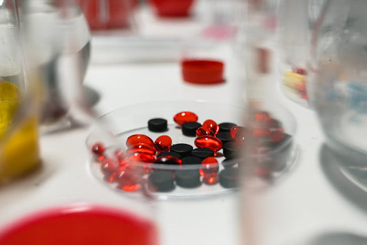 Close-up view of red and black pills on a lab table with blurred background.
