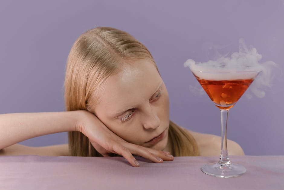 A woman in a spooky Halloween theme with a smoky cocktail on a purple background.